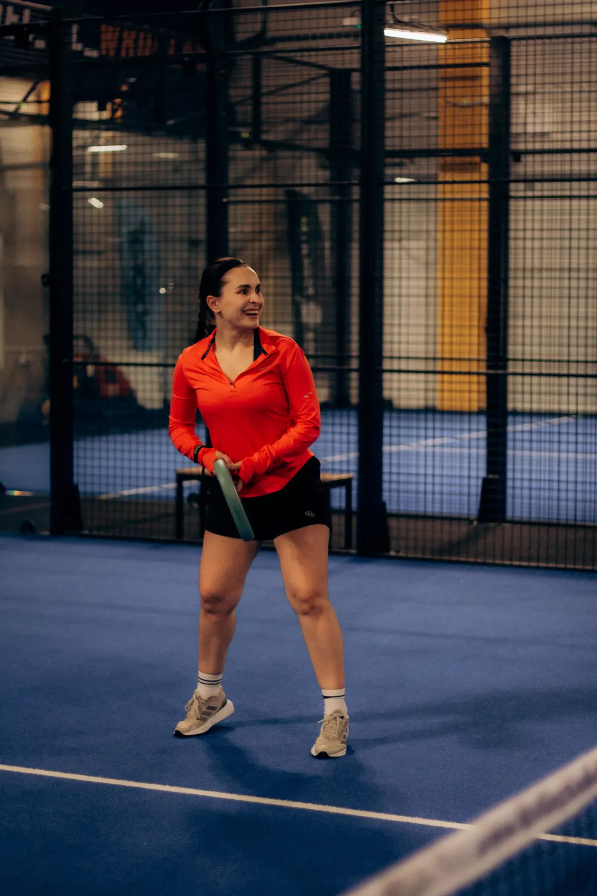 A padel player mid-game on a floodlit court